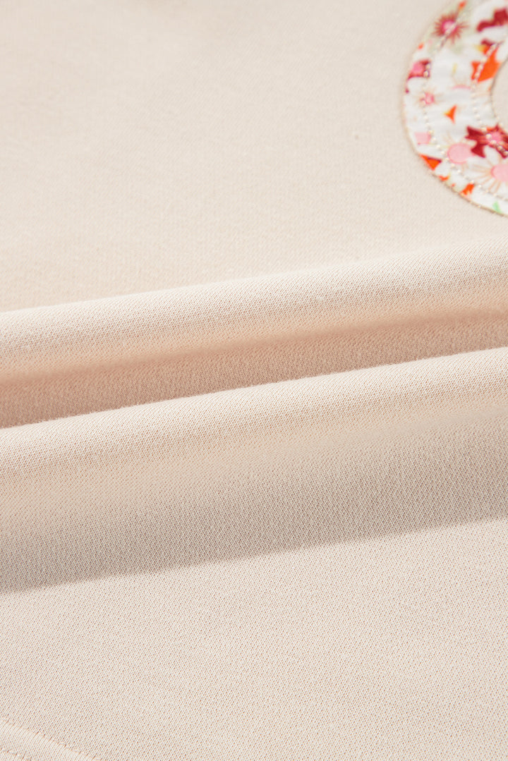 Oberteil mit Blumen-Patch-Grafik, sichtbaren Nähten und weiten Ärmeln