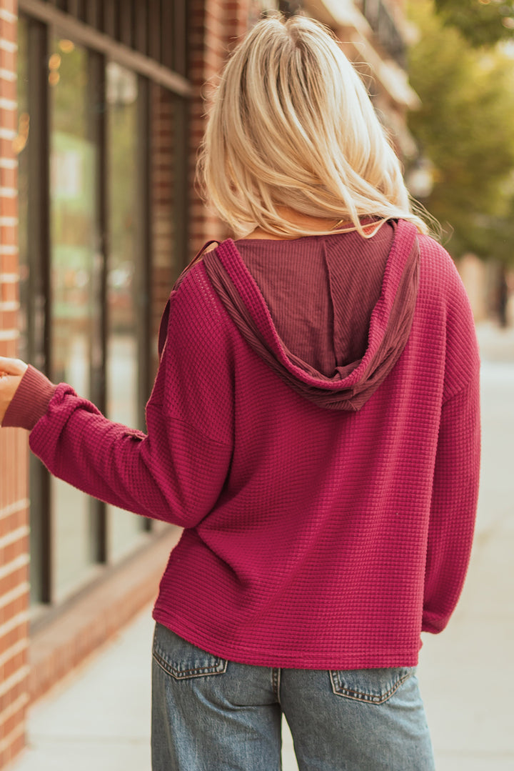 Rotes, langärmliges Oberteil mit Waffelmuster und überschnittener Schulterpartie und Kapuze